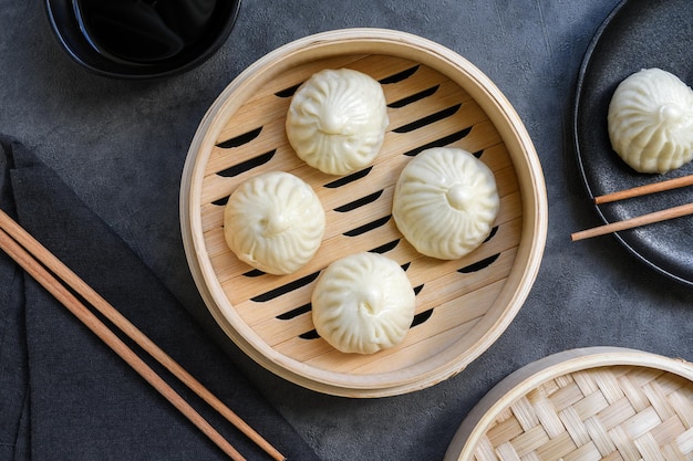 Cuiseurs à vapeur en bambou avec de délicieuses baguettes de boulettes de baozi et un bol de sauce