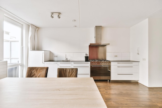 Photo une cuisine avec des armoires blanches et une table en bois