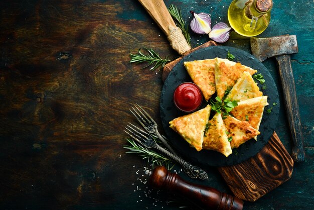 Cuisine asiatique Samsa avec poulet et fromage sur une plaque en pierre noire avec du ketchup Style rustique Vue de dessus