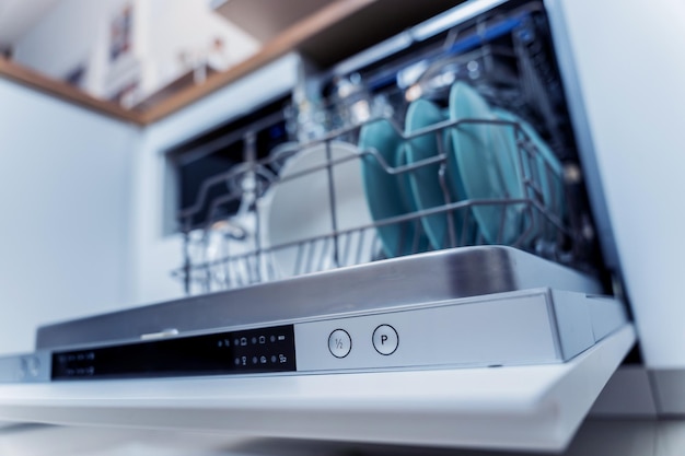 La cuisine blanche et le lave-vaisselle ouvert avec des plats propres