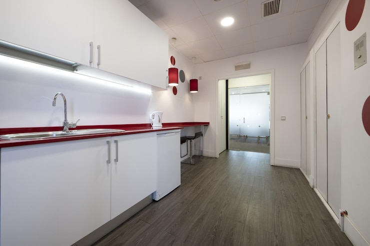 Photo cuisine d'un bureau de coworking avec un plan de travail rouge et des meubles blancs