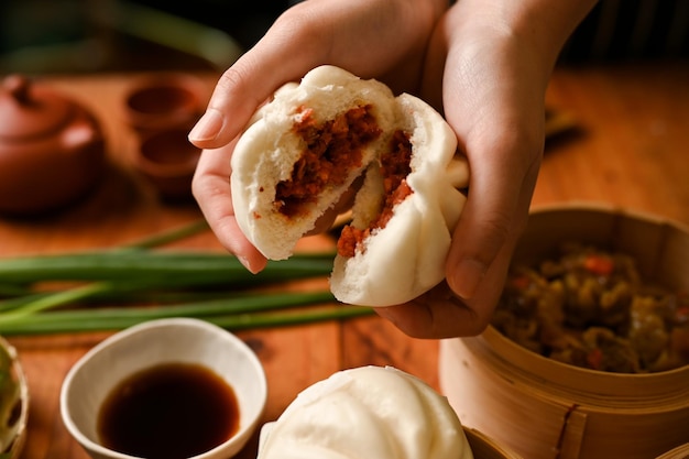 Cuisine chinoise dim sum Mains féminines tenant un petit pain de porc cuit à la vapeur