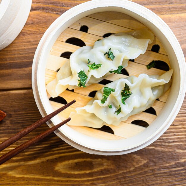 Cuisine chinoise à la vapeur du gyoza fumant close up sur table en bois