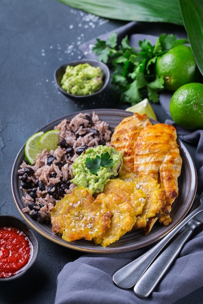 Cuisine colombienne cubaine traditionnelle des Caraïbes d'Amérique centrale Riz aux haricots noirs poitrine de poulet frite rôtie et tostones bananes vertes frites plantains avec sauce guacamole