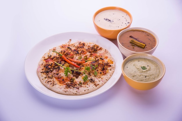 Cuisine du sud de l'Inde Uttapam ou ooththappam ou Uthappa est un plat de type dosa préparé en cuisinant des ingrédients dans une pâte, servi avec du chutney de noix de coco, du chutney vert et du sambar