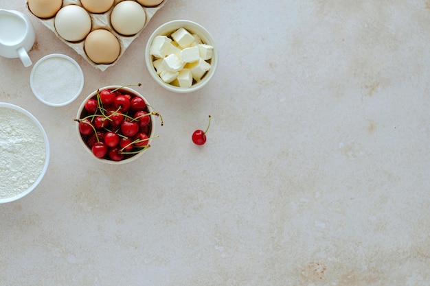 Cuisine d'été fond de cuisson avec des ingrédients cerises farine lait oeufs sucre beurre fouet