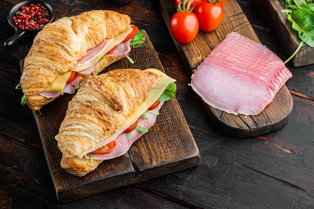 Cuisine française pour le petit déjeuner. Sandwich croissant cuit au four avec des verts de jambon et du fromage, avec des herbes et des ingrédients, sur le vieux fond de table en bois foncé