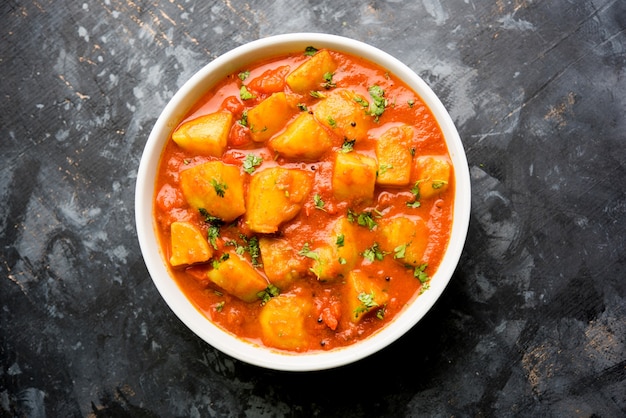 Cuisine indienne - Aloo curry masala. Pomme de terre cuite avec des épices et des herbes dans un curry de tomates. servi dans un bol sur fond de mauvaise humeur. mise au point sélective