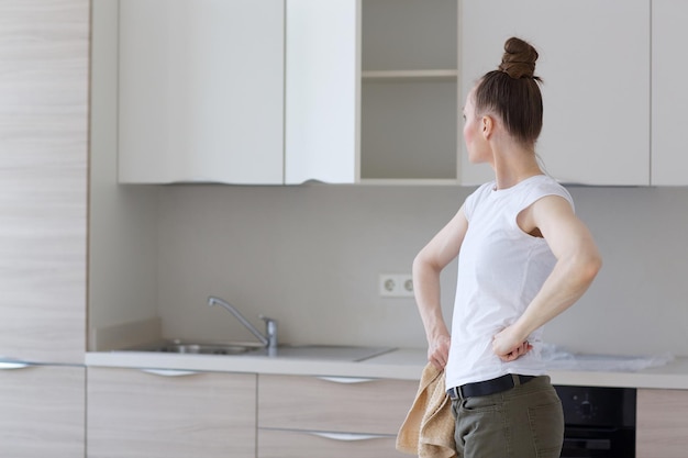 Cuisine installée dans un appartement neuf et jeune femme au foyer en face.