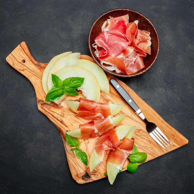 Photo cuisine italienne avec melon et prosciutto sur planche à découper en bois