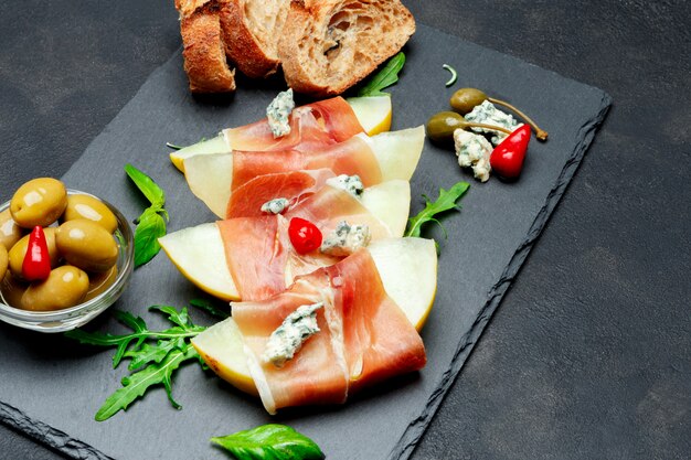 Cuisine italienne avec melon et prosciutto sur planche de pierre