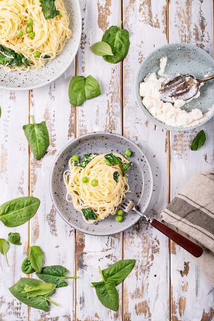 Cuisine italienne: pâtes fraîches aux oeufs végétariens tagliatelles Carbonara servi avec du fromage ricotta et des épinards sur fond de bois blanc