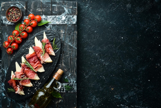 Cuisine italienne Prosciutto aux poires et sauce balsamique Jamon sur une assiette en pierre noire Vue de dessus