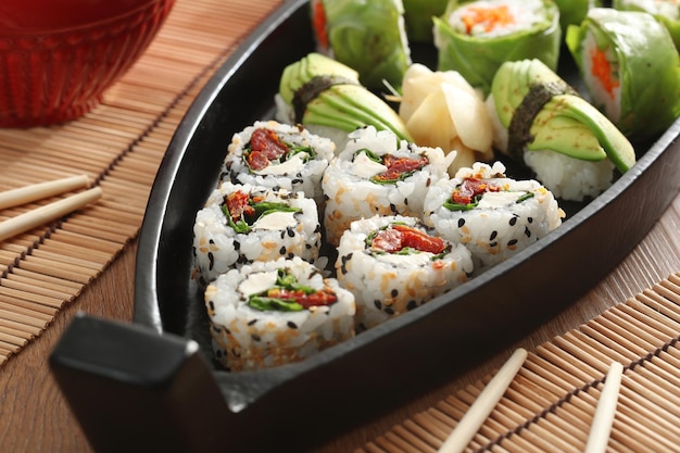 Cuisine japonaise et oignons croustillants servis au restaurant sur un bateau noir sur une table en bois