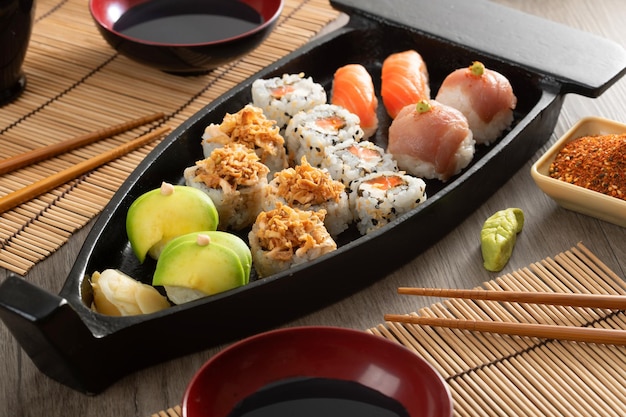 Cuisine japonaise et oignons croustillants servis au restaurant sur un bateau noir sur une table en bois