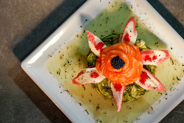 Cuisine japonaise Sunomono de saumon et kani kama sur une assiette carrée blanche Vue de dessus