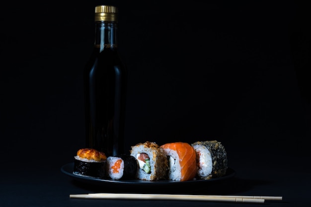 Cuisine japonaise sushi maki et nigiri sur fond noir sauce soja et bâtons de bois
