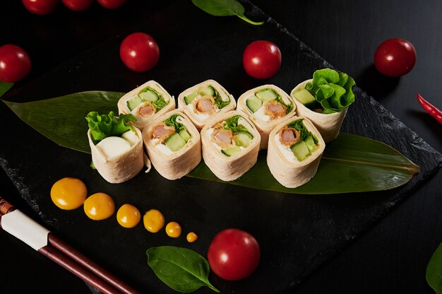 Photo cuisine japonaise traditionnelle - sushi, petits pains et sauce sur fond noir.