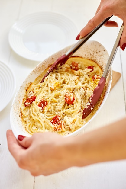 La cuisine de la main de femme tendance tomates cuites au four et feta aux pâtes