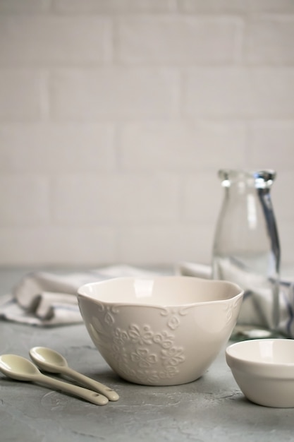 Cuisine maison simple nature morte sur une surface de murs clairs sur une table en béton gris. Ensemble de plats en porcelaine et bouteille en verre. Ustensile de cuisine