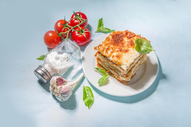 Cuisine méditerranéenne, pâtes à lasagnes traditionnelles italiennes, avec bolognaise, béchamel et fromage. Sur un fond bleu clair à la mode avec un espace de copie d'ombres claires et sombres