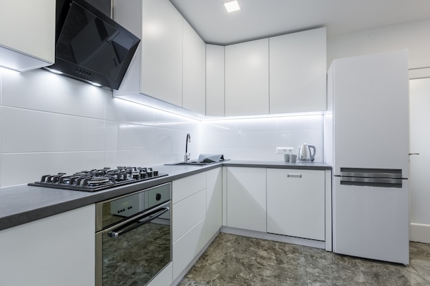 cuisine moderne dans des tons blancs clairs avec des carreaux de marbre noir au sol placé dans un petit appartement