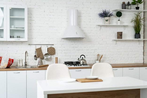 Une cuisine moderne avec un mur en brique blanche et des chaises blanches élégantes Une cuisine avec un mur de brique blanque et des chaires blanches