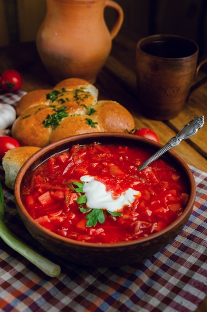 Cuisine nationale ukrainienne - bortsch rouge avec des beignets dans un bol en argile sur une table en bois.