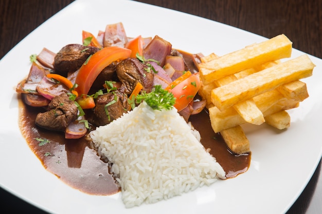 Cuisine péruvienne "lomo saltado": Un boeuf salé avec des tomates, des oignons, des pommes de terre frites et du riz.