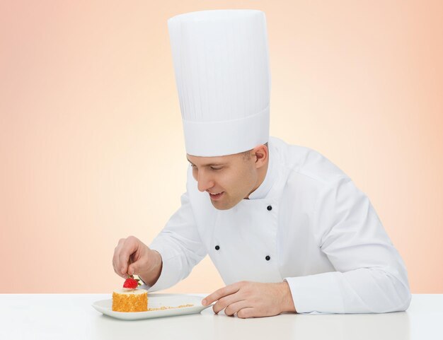 cuisine, profession, haute cuisine, concept de nourriture et de personnes - heureux chef cuisinier décorant le dessert sur fond beige