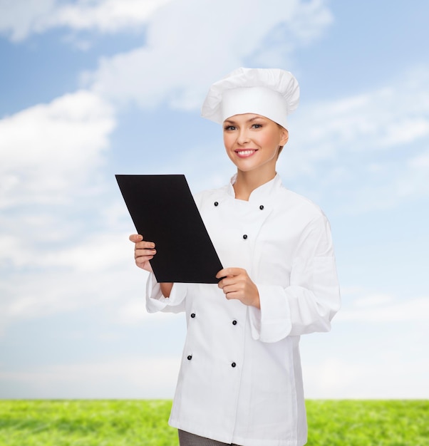 cuisine, publicité et concept alimentaire - chef féminin souriant, cuisinier ou boulanger avec du papier de menu noir vierge