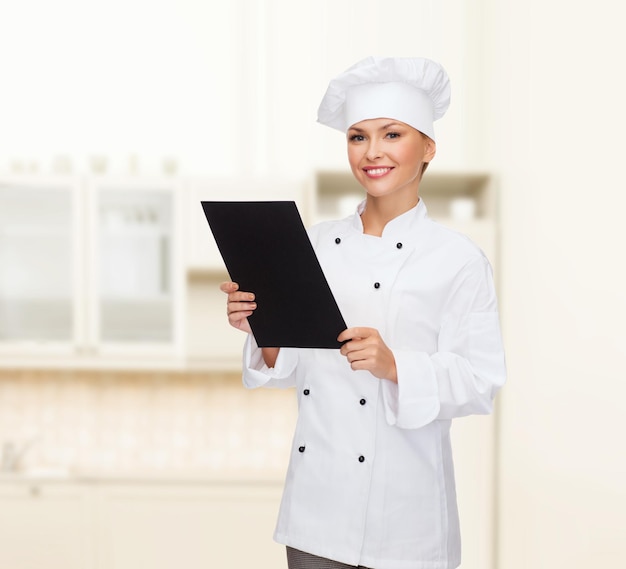 cuisine, publicité et concept alimentaire - chef féminin souriant, cuisinier ou boulanger avec du papier de menu noir vierge