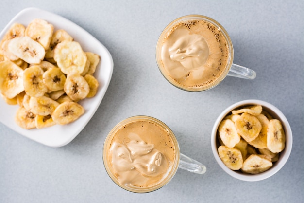 Cuisine de quarantaine. Deux tasses de café dalgona et chips de banane sur fond gris. Vue de dessus