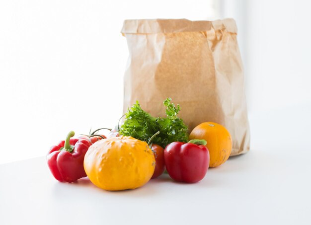 cuisine, régime alimentaire, nourriture végétarienne et concept d'alimentation saine - gros plan d'un sac en papier avec des légumes frais mûrs juteux, des verts et des fruits sur la table de la cuisine à la maison