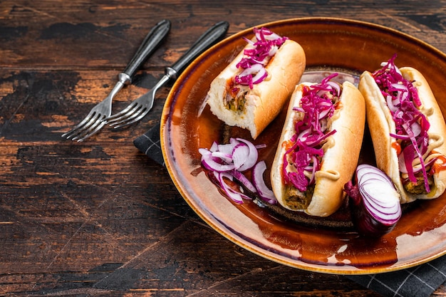 Cuisine de rue - Hot-dogs végétaliens avec chou et saucisse sans viande. Fond en bois sombre. Vue de dessus. Espace de copie.