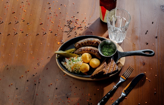 Cuisine rustique avec saucisse rôtie pommes de terre frites sur une assiette avec des couverts, vue du dessus. Concept de cuisine allemande