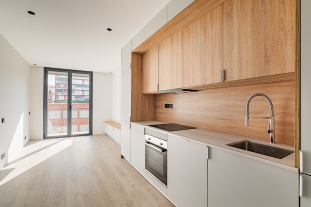 Cuisine et salon minimalistes contemporains avec balcon dans un appartement rénové vide meublé en bois ...