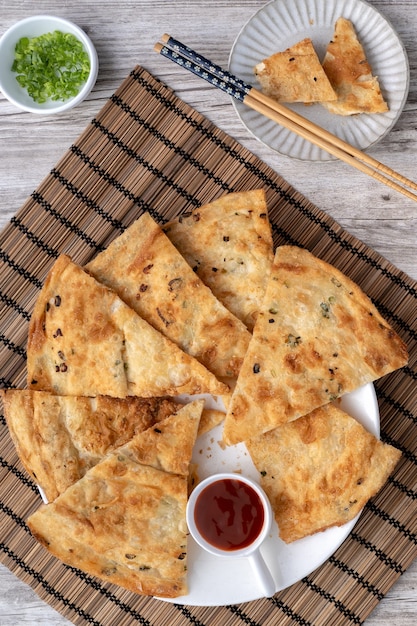 Cuisine taïwanaise - délicieuses crêpes à la tarte aux échalotes feuilletées sur fond de table en bois clair, collation traditionnelle à Taïwan, vue de dessus.