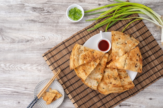 La cuisine taïwanaise de délicieuses crêpes à la tarte aux oignons verts feuilletés sur table en bois clair