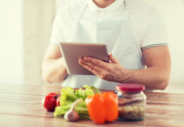 cuisine, technologie et concept de maison - gros plan d'un homme lisant une recette à partir d'un ordinateur tablette pc