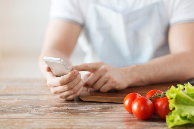 cuisine, technologie et concept de maison - gros plan sur un homme pointant du doigt un smartphone