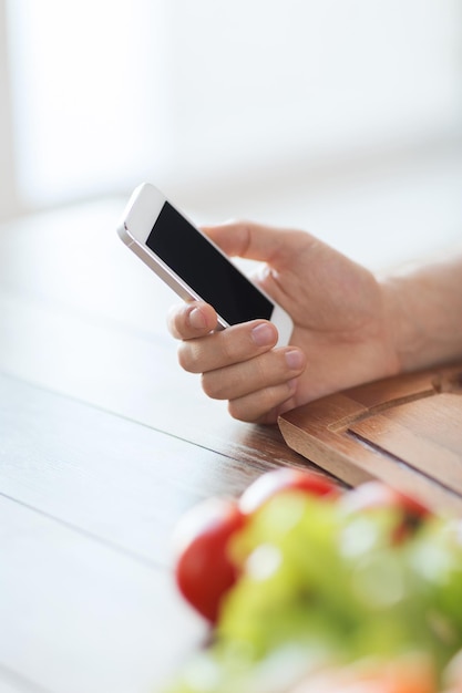 cuisine, technologie et concept de maison - gros plan sur un homme avec un smartphone