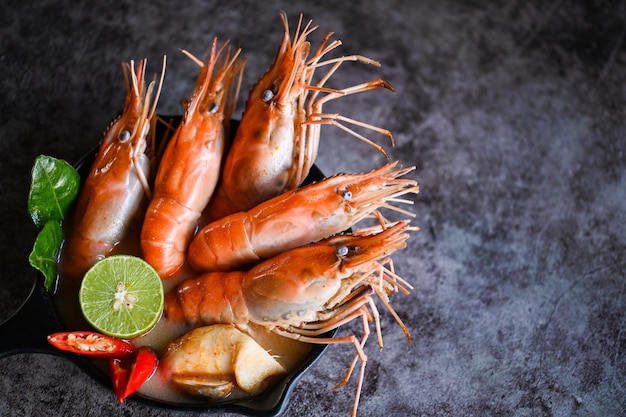 Cuisine thaïlandaise Tom Yum Kung Crevettes épicées chaudes et aigres soupe de crevettes curry citron vert galanga piment rouge champignon de paille sur la nourriture de table Soupe de crevettes sur bol de soupe de fruits de mer avec herbes et épices thaïlandaises