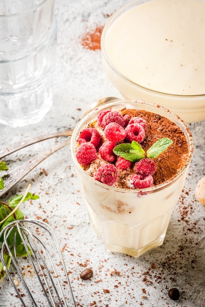 Cuisine Tiramisu, dessert italien, avec tous les ingrédients nécessaires: cacao, café, mascarpone, menthe et framboises