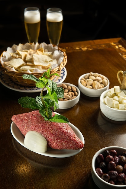 Cuisine traditionnelle du Moyen-Orient. Cuisine libanaise. Kibbeh cru arabe, olives, fromage, verre à bière