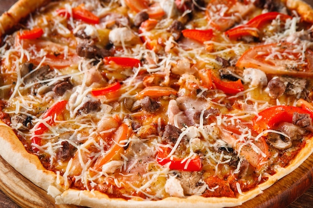 Cuisine traditionnelle italienne. Délicieuse pizza maison fraîche avec tomate, jambon, poulet et champignons, vue rapprochée.