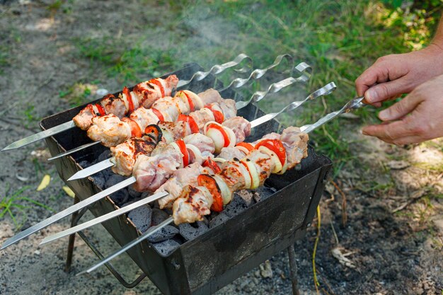 Cuisiner un barbecue avec des légumes sur des brochettes de viande rôtie sur le gril en gros plan