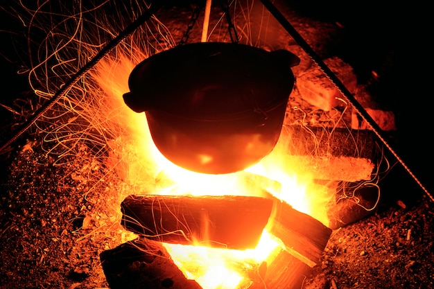 Cuisiner sur le bûcher la nuit. Grande flamme