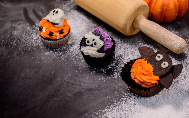 Photo cuisiner de délicieux gâteaux faits maison et décorer des cupcakes pour la fête d'halloween. préparer et mélanger des ingrédients pour un dessert sucré dans la cuisine à la maison.