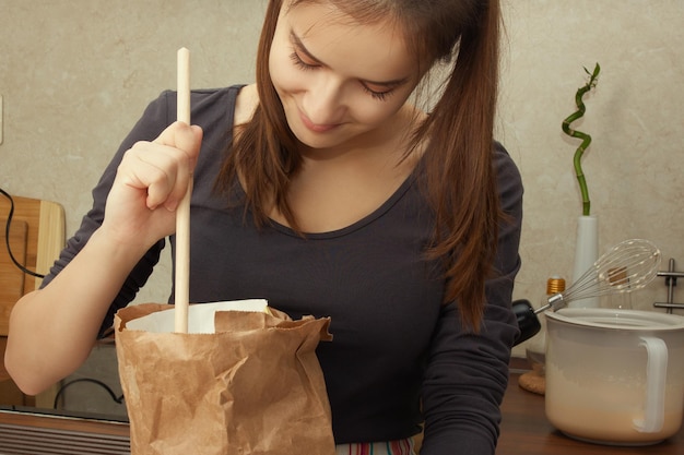 Cuisiner un dessert. Fille ajoute de la farine dans une tasse à mesurer dans la cuisine.